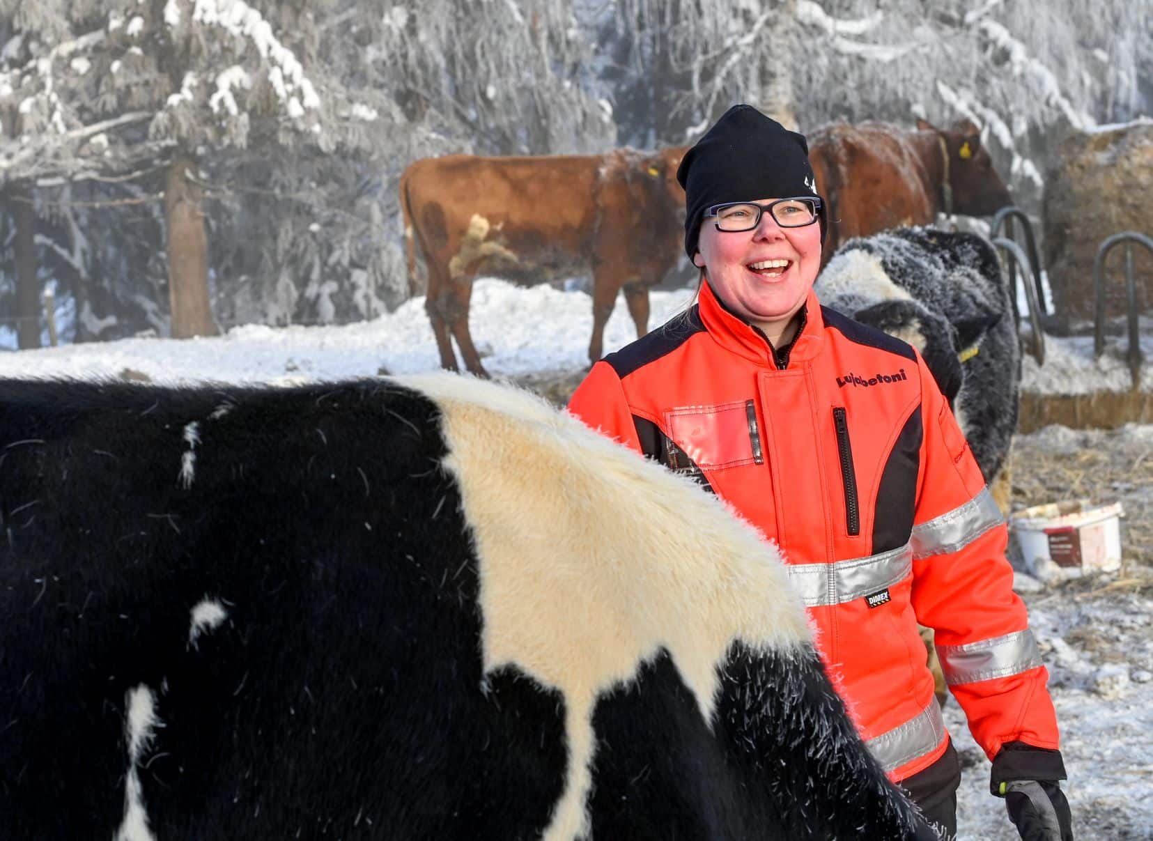 Kuva, jossa nainen ja lehmä talvisessa maisemassa.