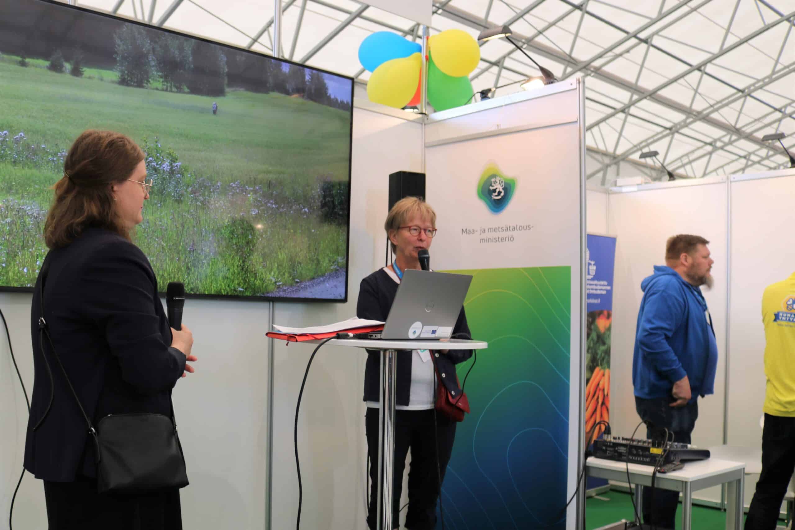 Leena Pietilä puhuu messulavalla mikrofoniin.