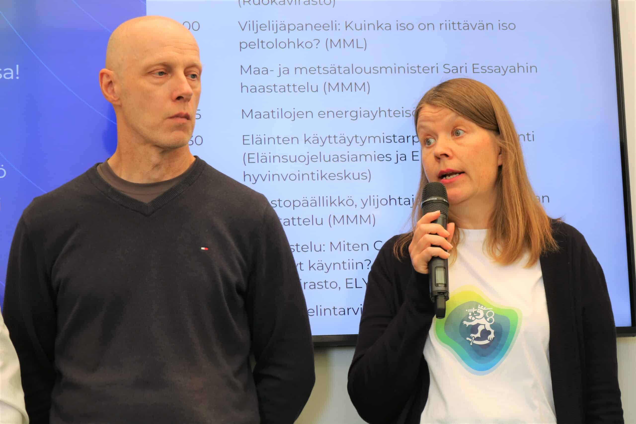 Kaksi ihmistä messulavalla. Vasemmalla Markku Paija ja oikealla Sanna Koivumäki mikrofoni kädessään.