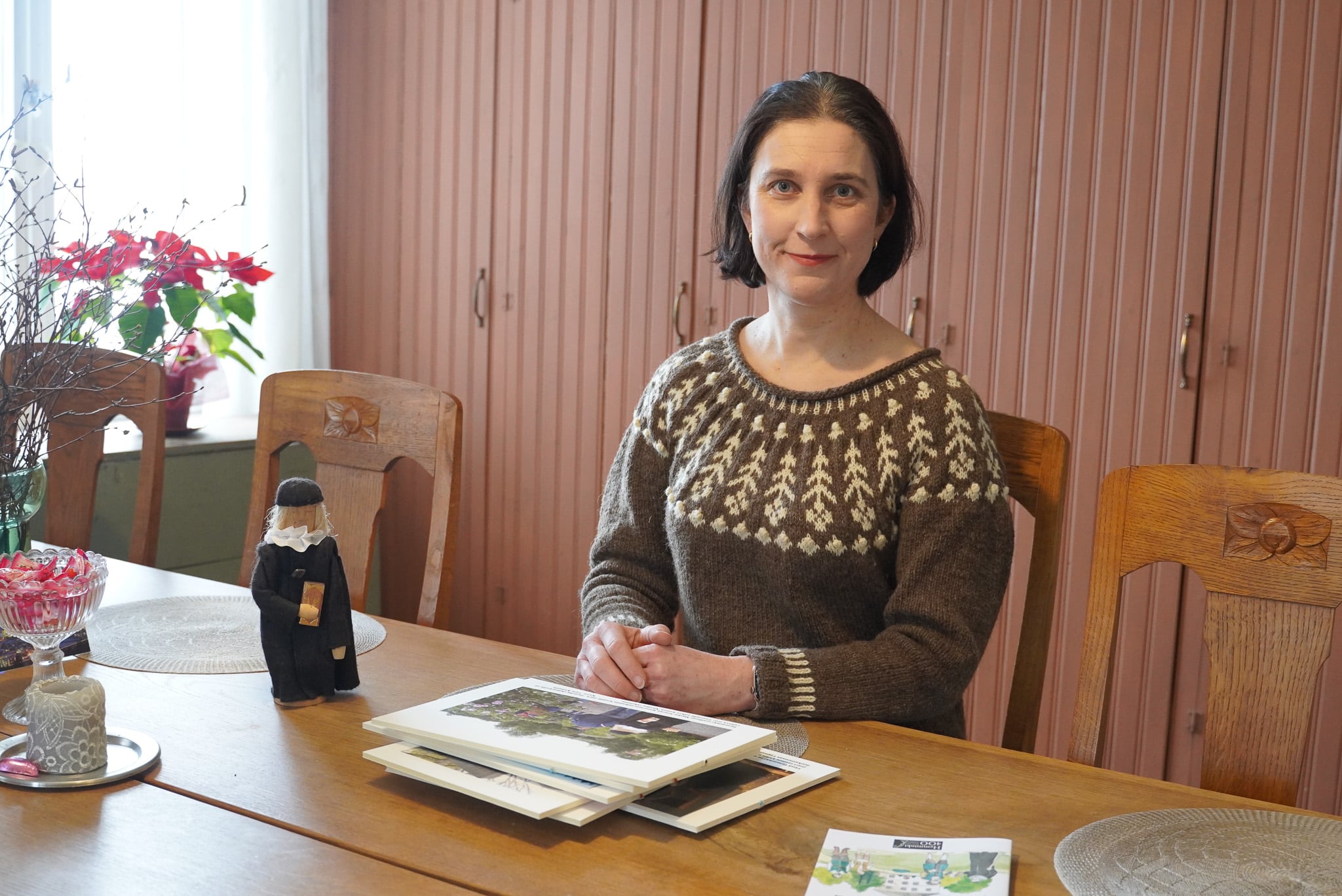 Marjukka Kulmala pöydän ääressä. Pöydällä on Hemminki Maskulaista esittävä nukke.