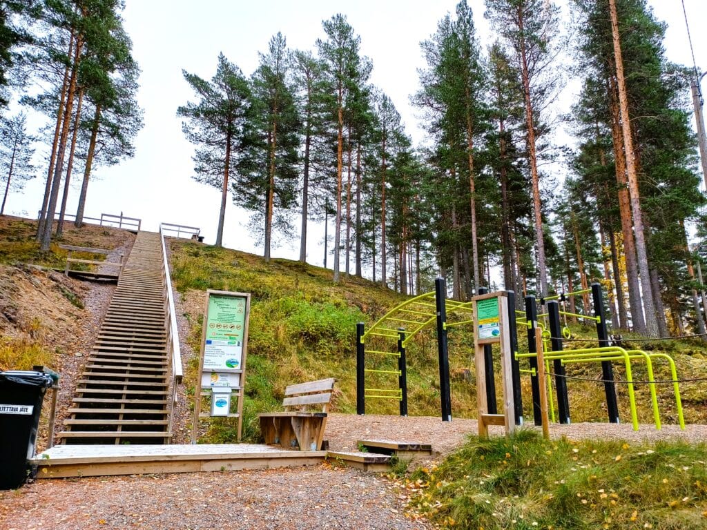 puiset kuntoportaat jotka nousevat ylös metsäistä rinnettä, portaiden juuressa ulkokuntolaitteita.
