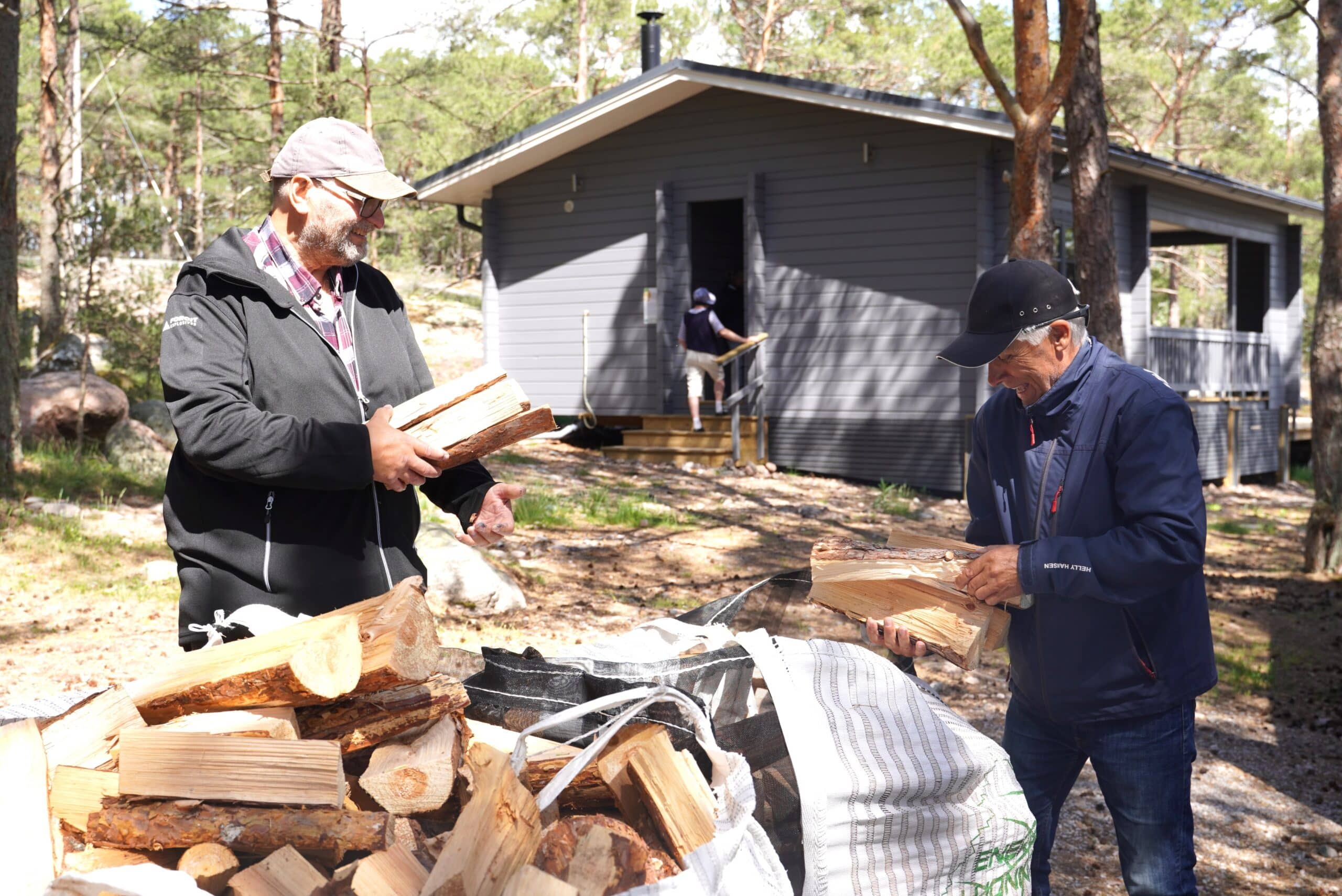 Kaksi miestä halkokasan äärellä.