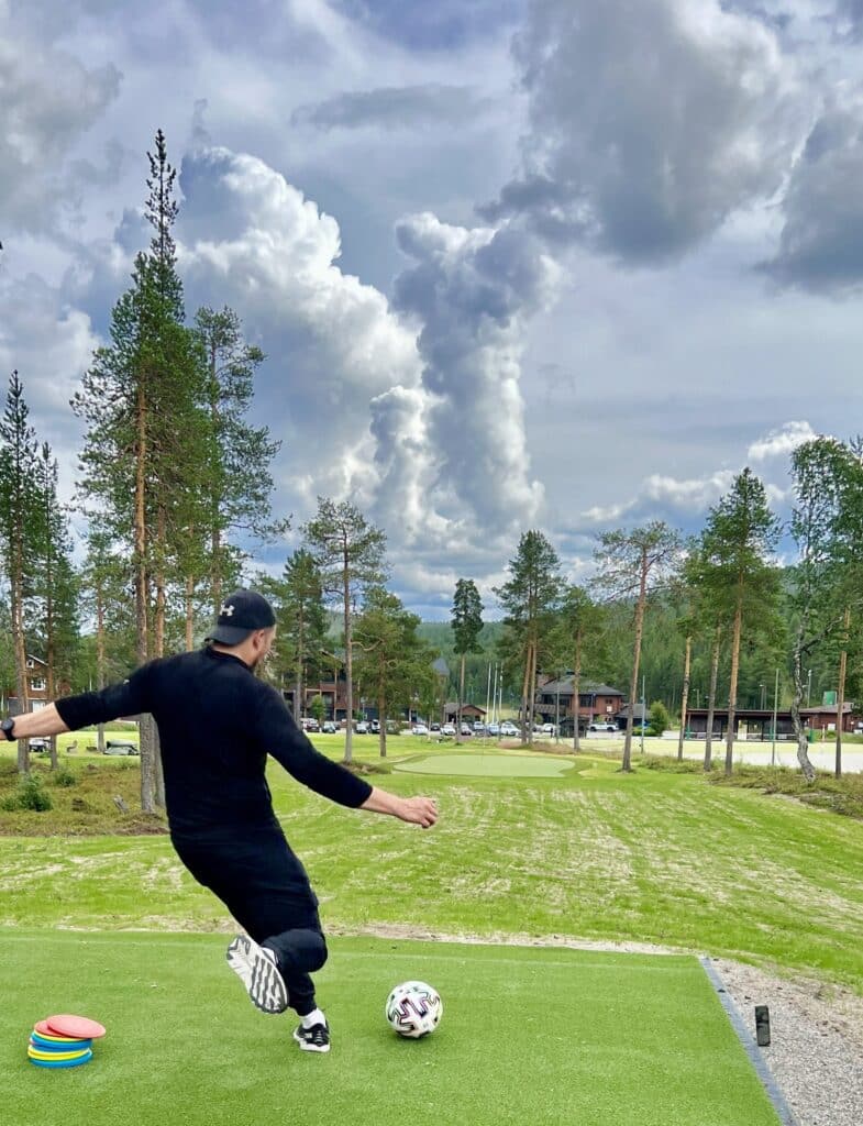 Mies potkaisee palloa.