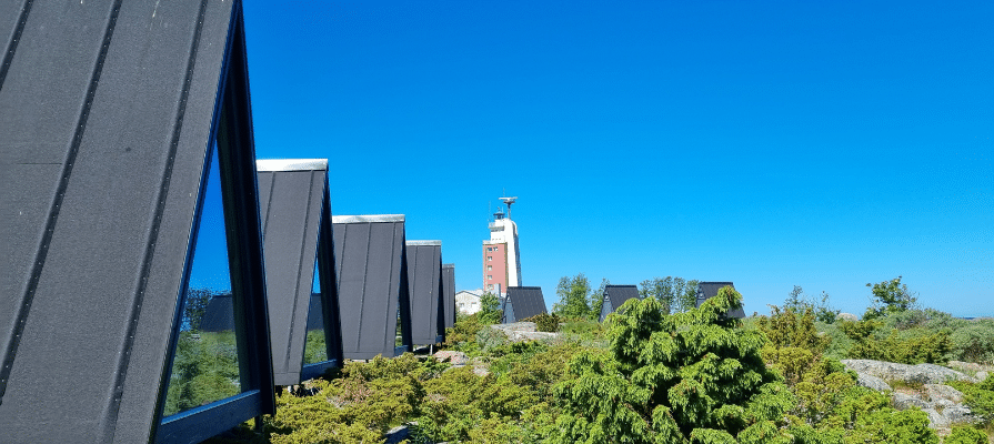 Lasiseinäisiä kolmion muotoisia pieniä mökkejä saaressa.