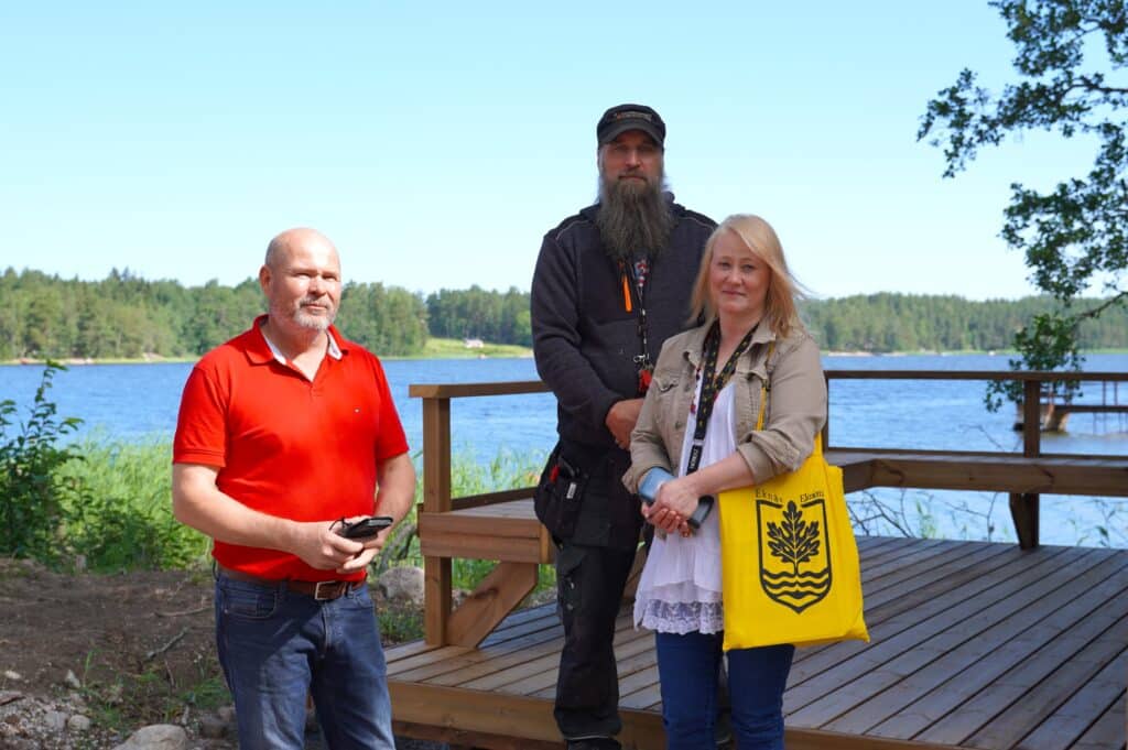 Kolme ihmistä lossinvartijan tuvan terassilla.