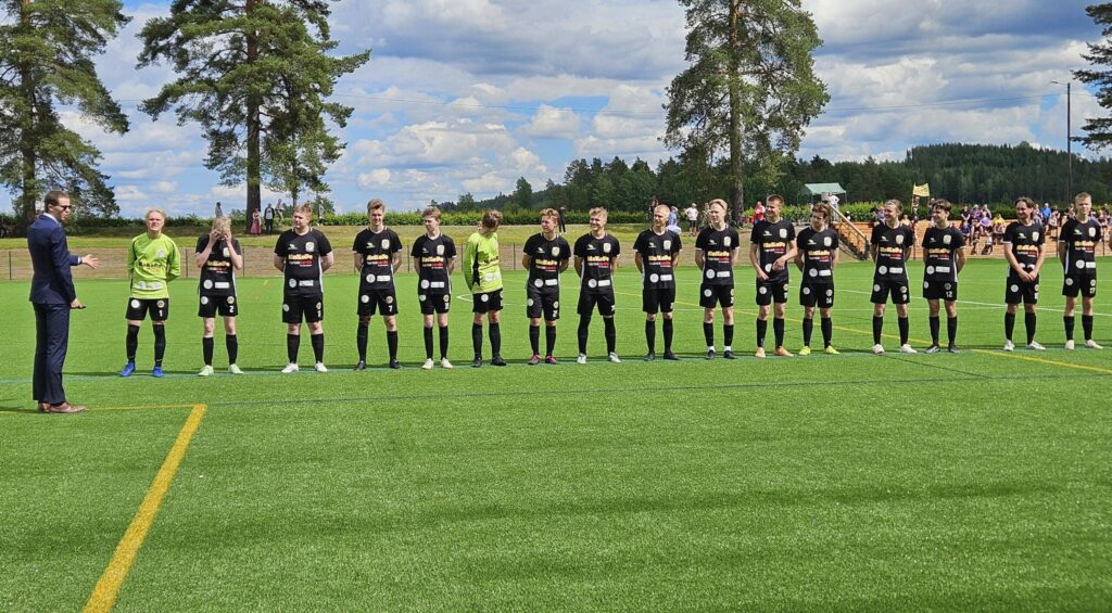 Jalkapallojoukkueen jäsenet rivissä kentällä.