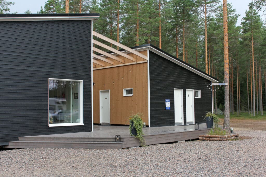 Puinen vastaanottorakennus, jonka edustalla on terassi. Takana näkyy mäntymetsää.