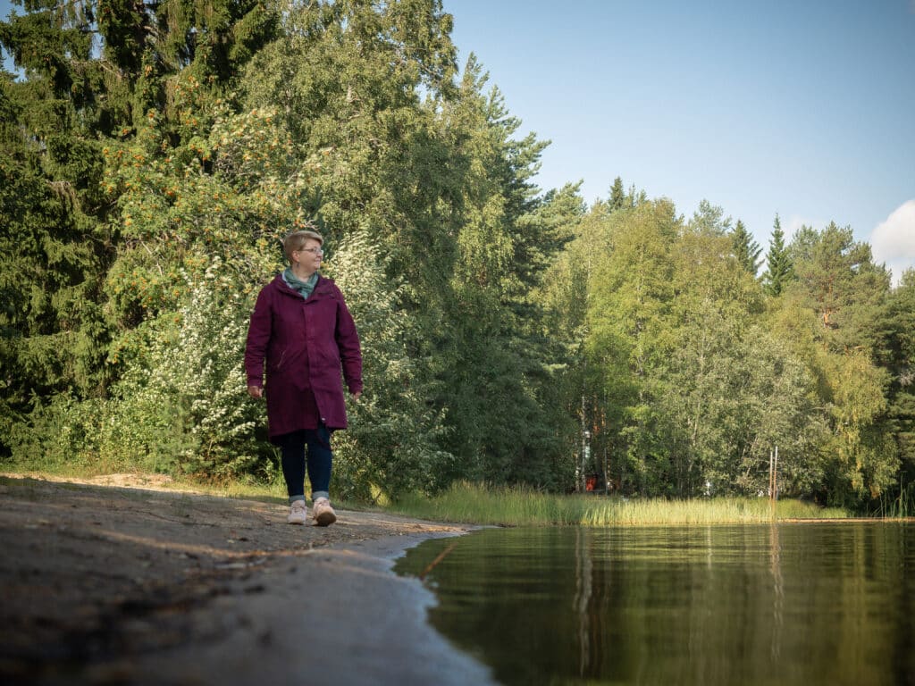 Nainen kävelee järven rannalla
