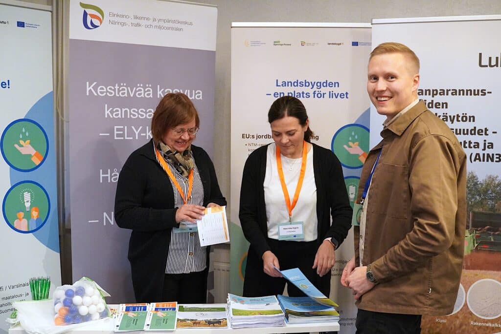 Kolme ihmistä esittelypisteellä.