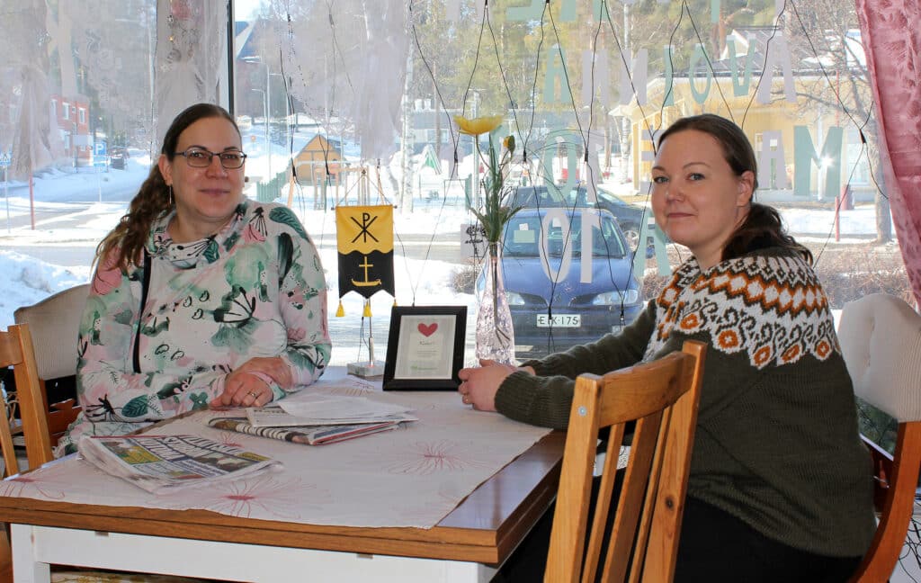 Kaksi naista istuu pöydän äärellä.