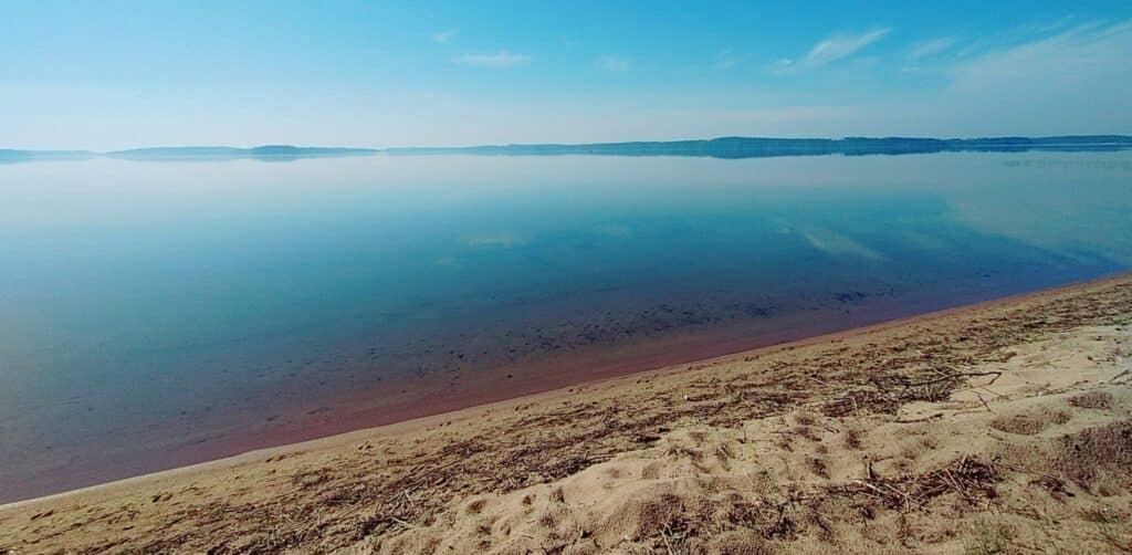 Hiekkarantaa ja sininen järvi ja taivas.