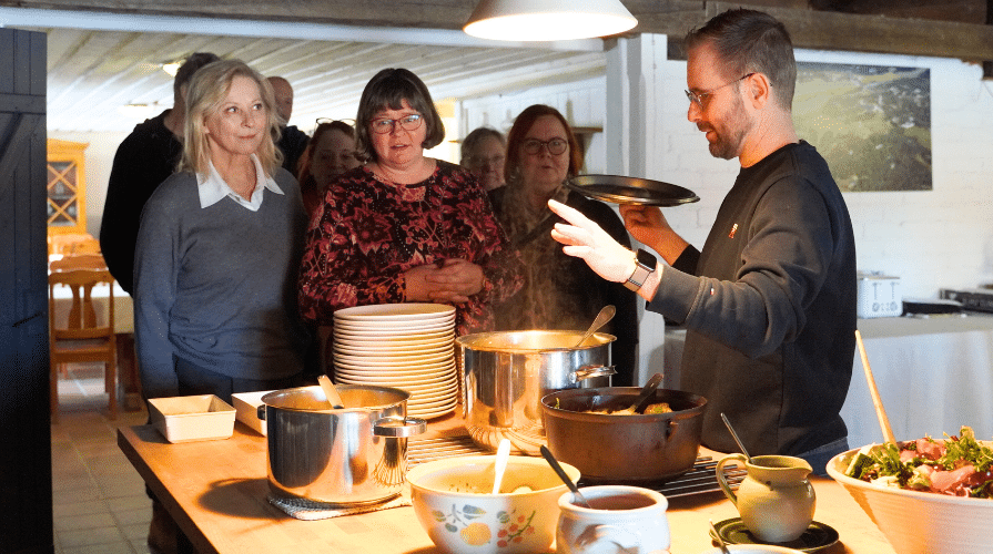 Mies esittelee noutopöytää, johon vieraat jonottavat.