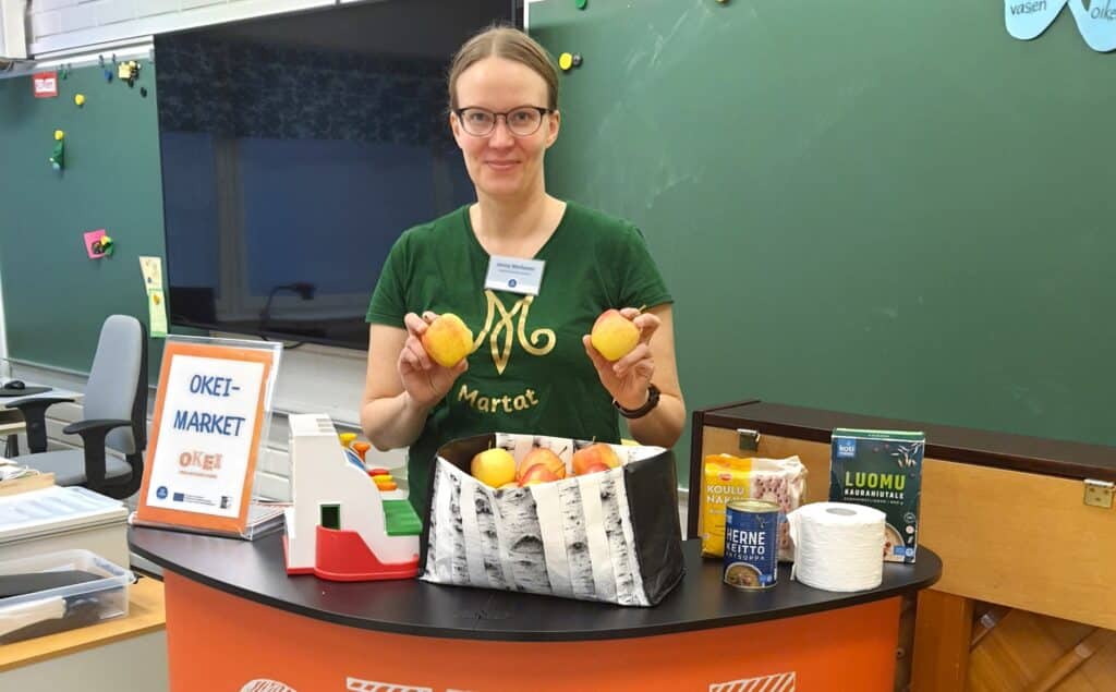 Nainen marttapaidassa koululuokassa.
