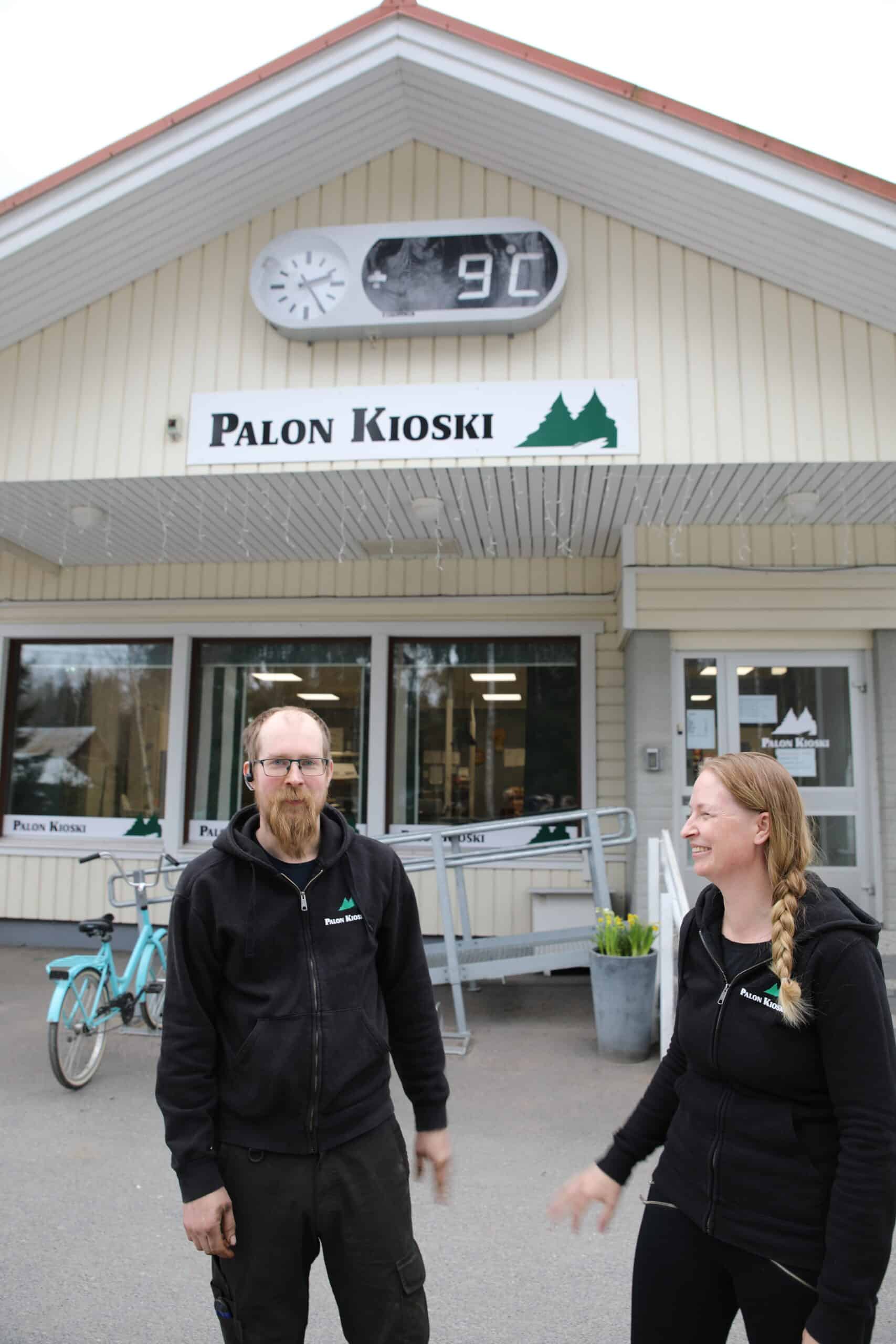 Kauppiaat Palon kioskin edessä ulkona. Keltaisen kioskin seinässä lukee Palon kioski.