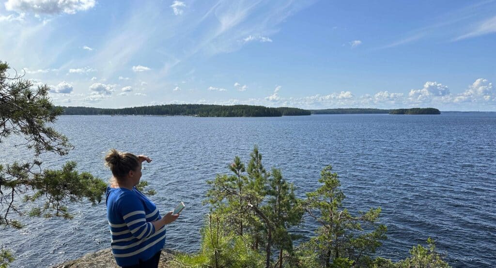 Nainen tähyilee korkealta paikalta kauas järvelle.