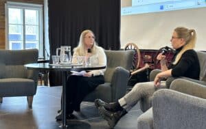 Kaksi naista esiintymislavalla. Toinen puhuu mikrofoniin.