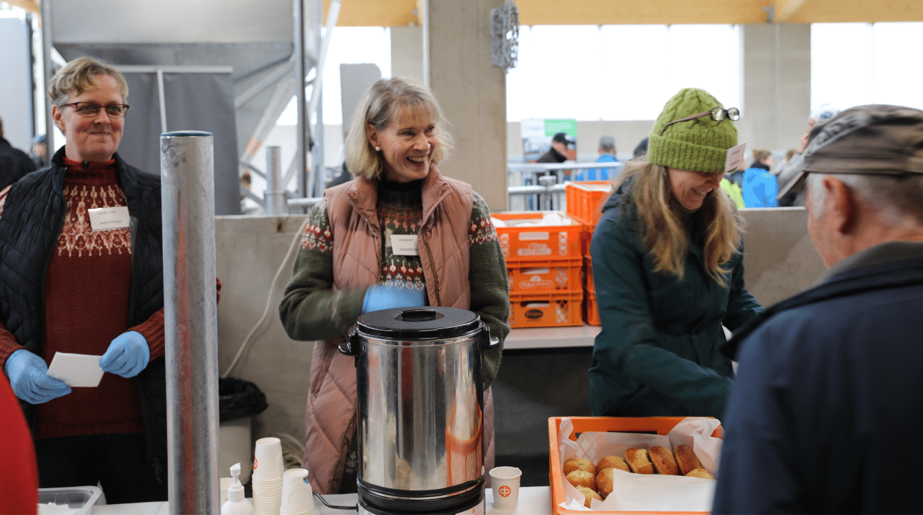 Naiset tarjoilevat kahvia ja pullaa tiskin takaa.