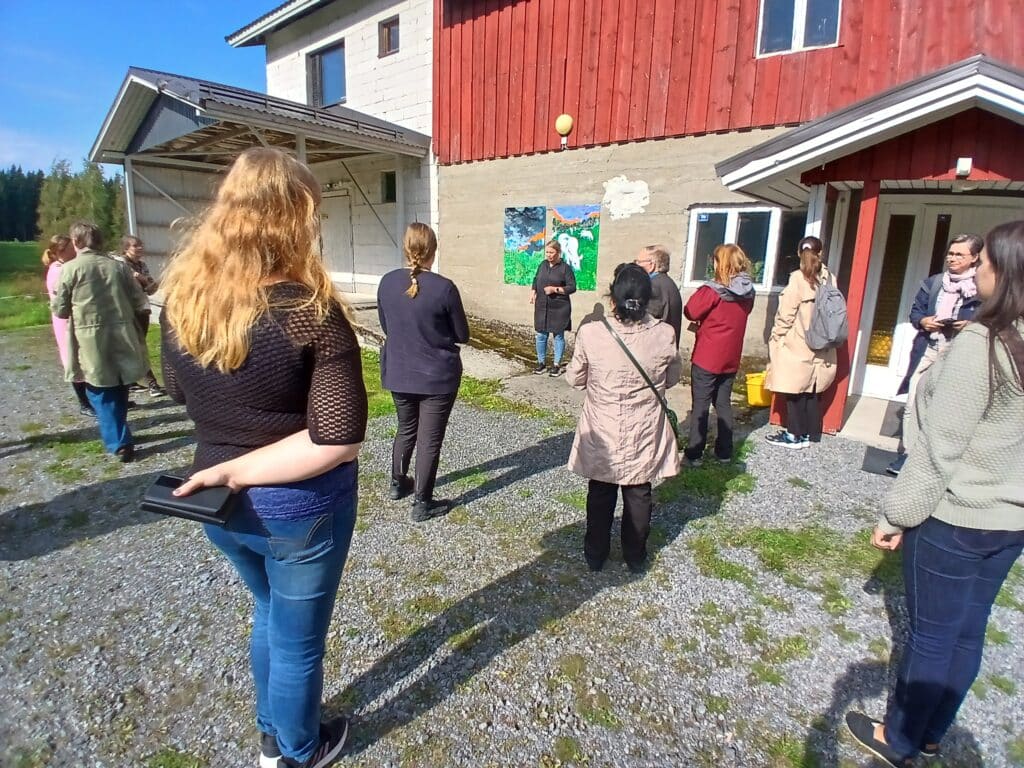 ihmisiä vanhan navetan edessä