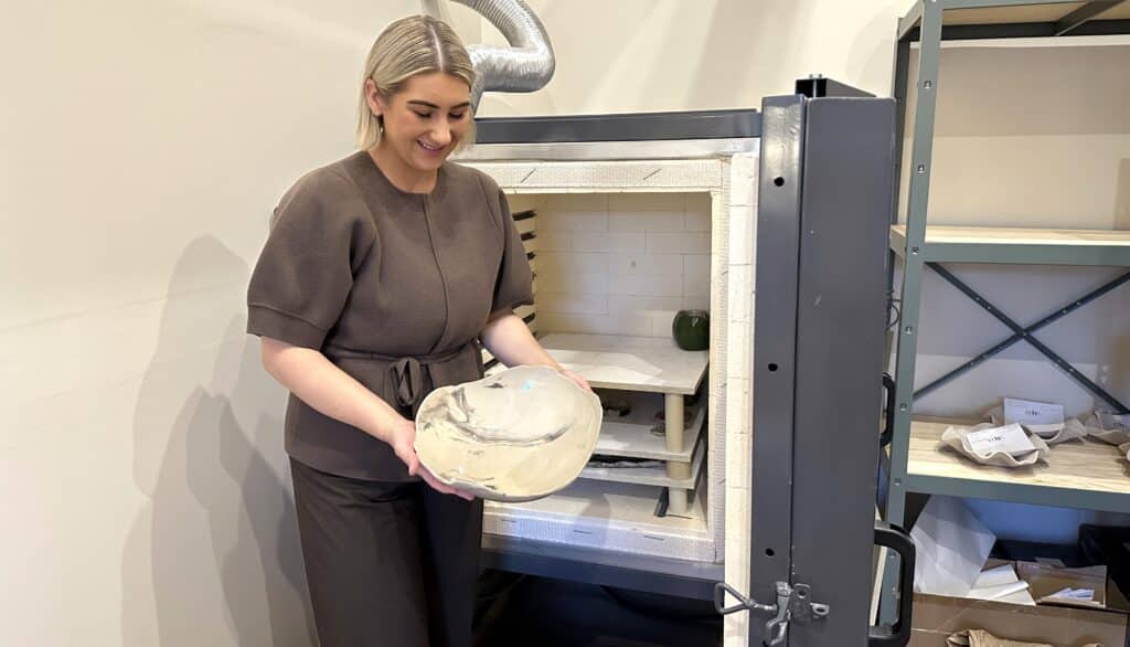 Nainen ottaa keramiikkauunista suuren vadin.