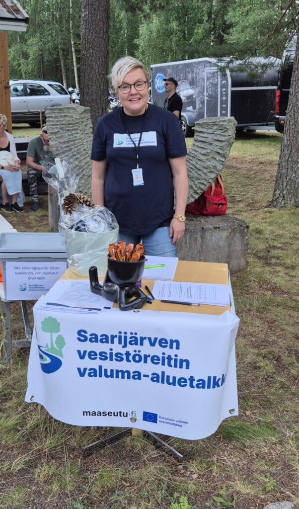 Nainen esittelypöydän takana kesätapahtumassa.