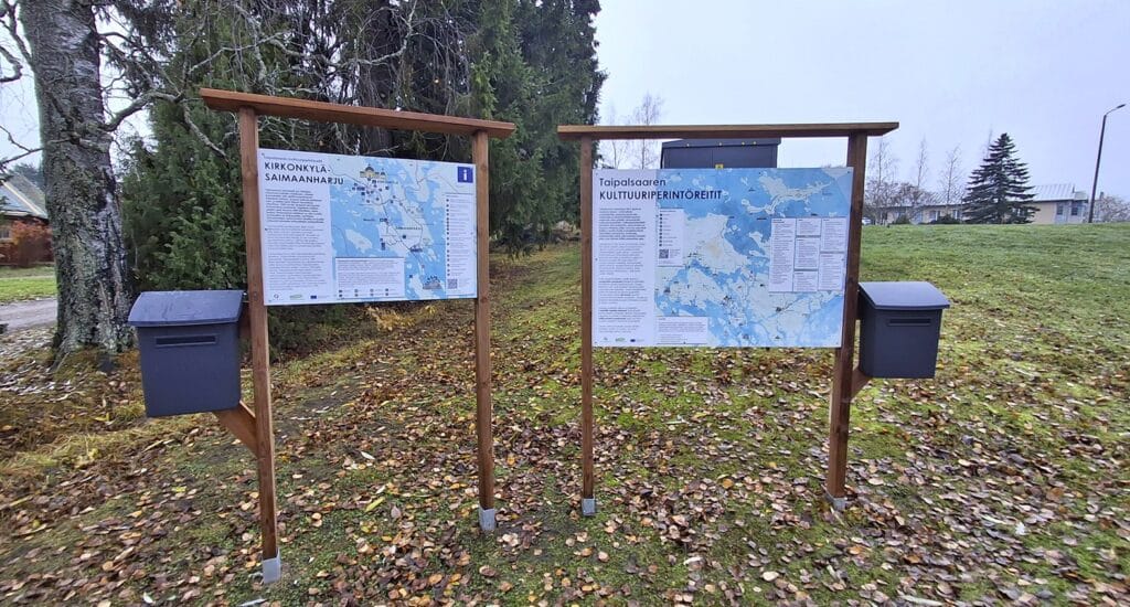 Infotauluja Taipalsaaren kirkonkylällä. Taustalla näkyy kunnantalo.