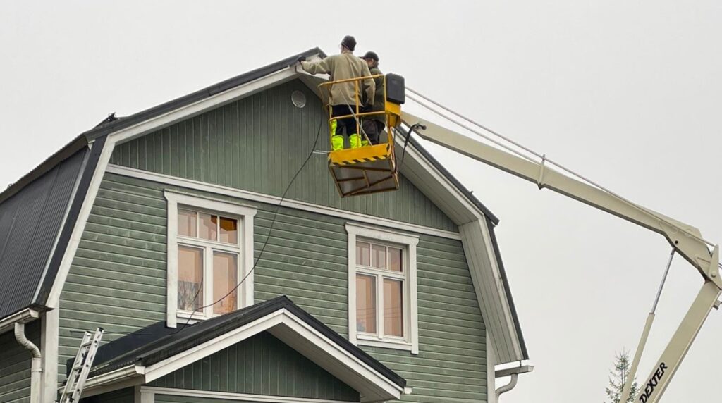 Talon harjalle asennetaan antennia nostokurjestä käsin.