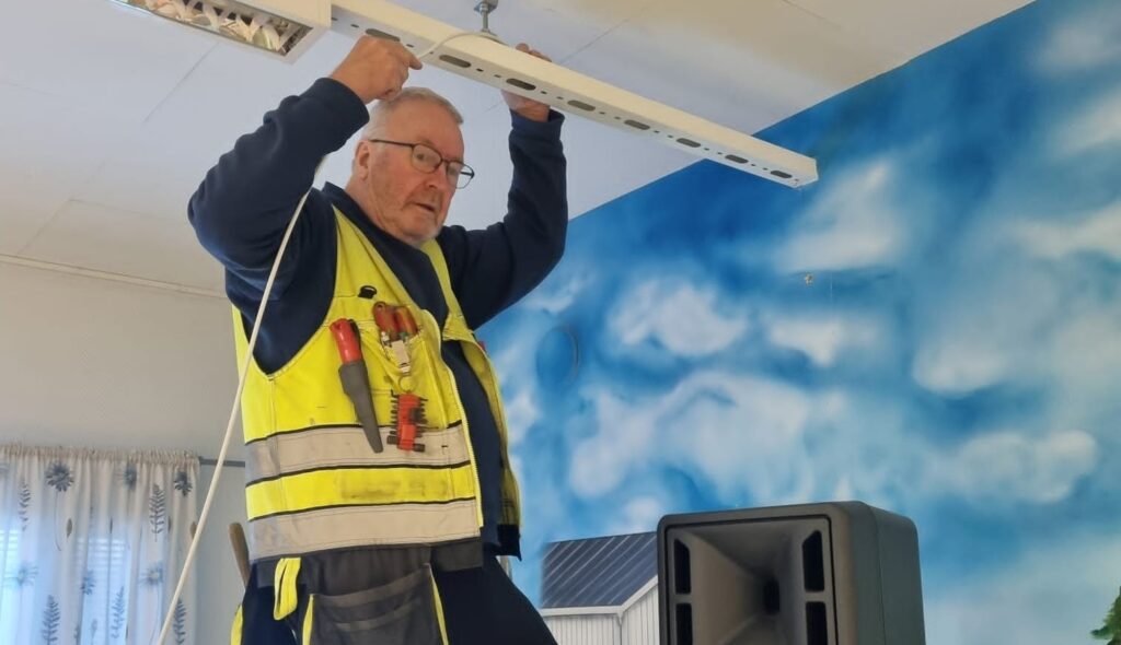 Mies laittaa johtoja kiinni kattolamppuun.