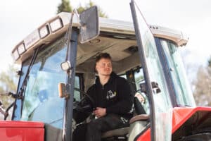 Mies istuu traktorissa ovi auki